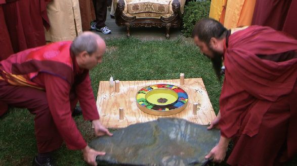 （圖三）兩位仁波切將大青石板抬起來，壓在曼達拉盤上，由應考者在石板上面採砂築壇畫圖，當抬開石板後，都失敗了